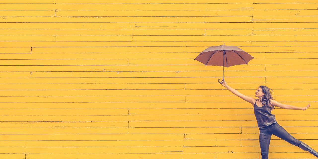Woman with umbrella against yellow background